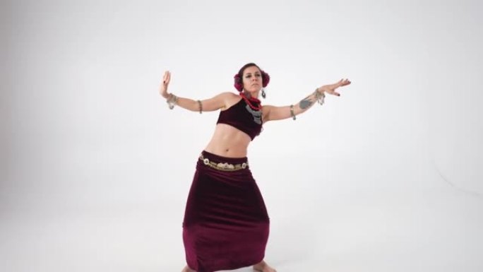 自信的女人手臂纹身跳舞中东舞蹈慢动作转向白色背景。现场摄像机缩小了优雅的高加索表演者摆姿势移动的手。