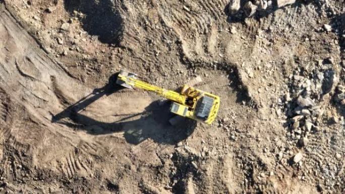 工业矿山挖掘机正在挖掘施工现场的土壤并装载卡车。空中无人机俯视图。