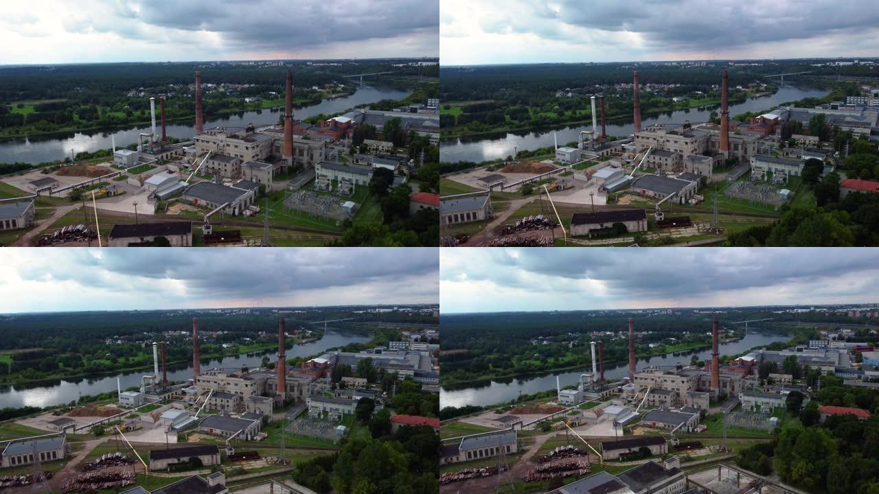 在树木和多云的天空的背景下，沿河的工厂和建筑物的4k航拍画面