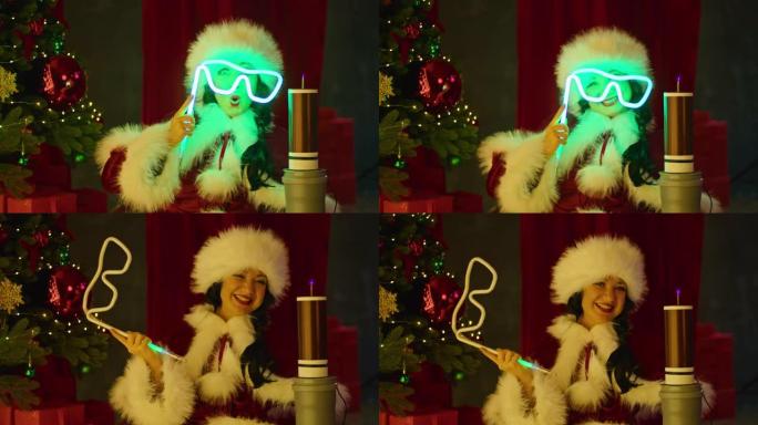 圣诞老人服装中的幸福女人在圣诞树的背景下，在特斯拉线圈附近玩霓虹灯管。新年秀，儿童假期。