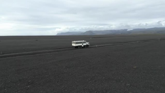 在冰岛，一辆越野改装的公共汽车快速驶出道路的侧面拍摄，鸟瞰图