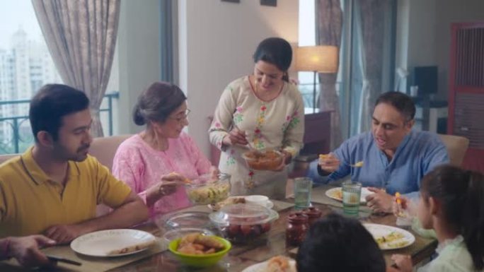 印度家庭的父母，祖父母，孩子们在室内的家中吃午饭。