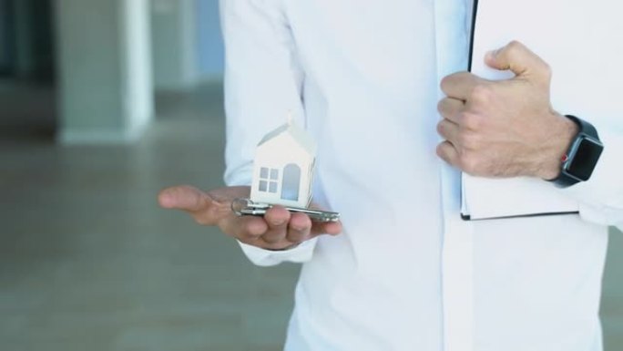 一名男子房地产经纪人手里拿着白宫模型和房子钥匙。按揭贷款审批房屋贷款及保险概念