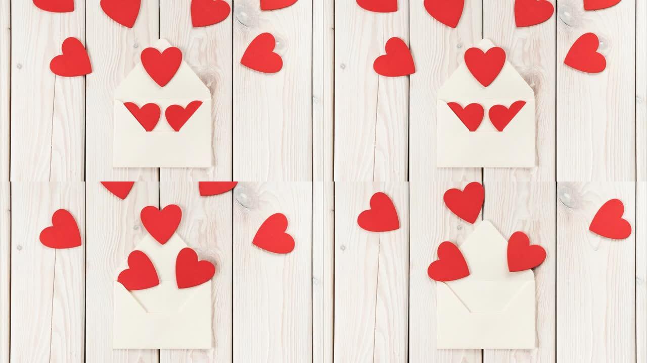 小红心从白色木制背景上的白色信封中移动。假期情书。婚礼或情人节