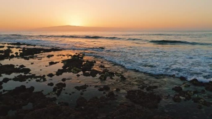 大自然母亲。惊人的海洋海滩。五颜六色的日落天空，太阳落在山岛戈梅拉后面。美丽的大自然。平静的海浪在岩