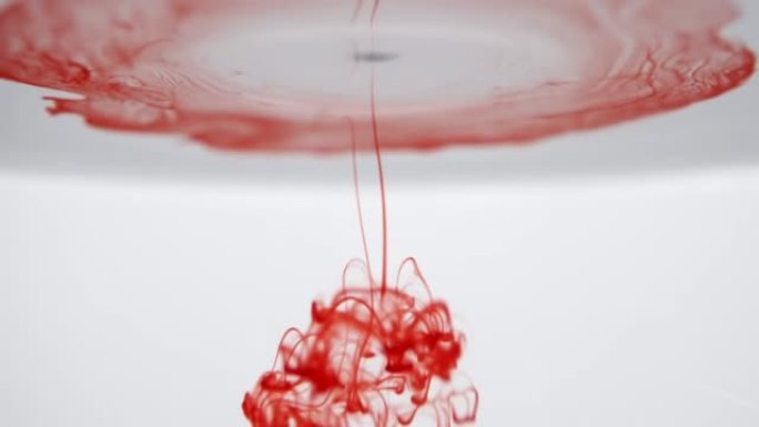 红色的墨水像真实的血液在白色背景上滴入水中，血滴在水中溶解