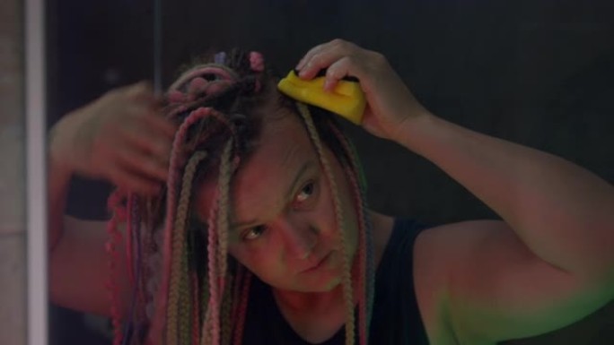 有箱形辫子发型的女人正在用海绵洗头皮。