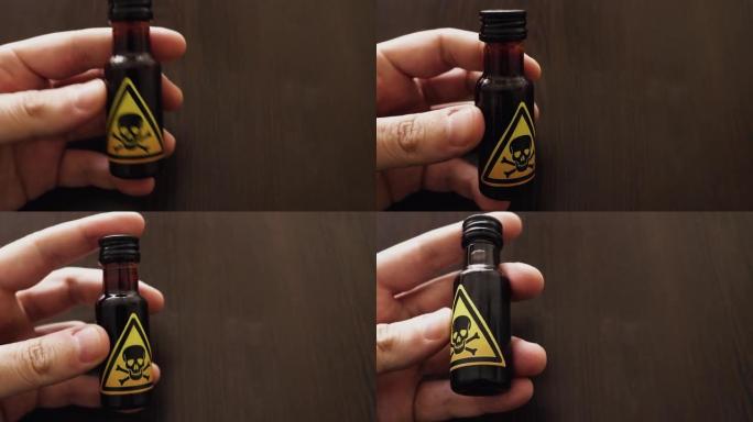 手拿着一小瓶带有黄色毒性标志的毒药，由头骨和两块骨头图标表示-危险的混合物或冲泡中毒，以饮用或注射
