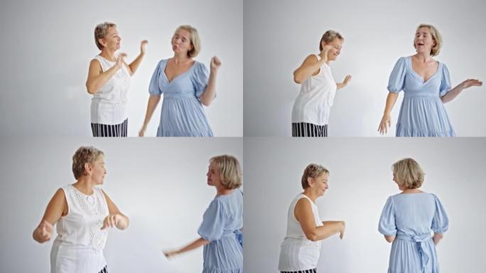 微笑的60多岁妈妈和成年的千禧一代女儿一起跳舞。喜出望外的成熟母亲和成年女童玩得开心，享受家庭休闲周