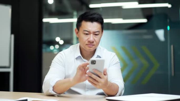 愤怒的恼怒的亚洲商人在办公室使用智能手机故障无法输入数据没有弱互联网网络男性用户对不良感到沮丧