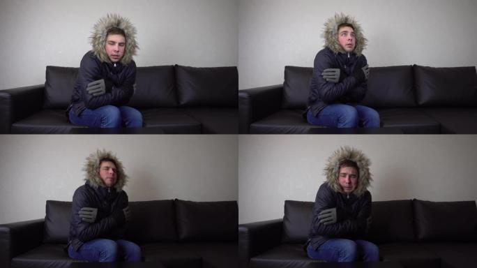 一个年轻人穿着冬季夹克坐在家里，试图保暖。这个人的电被切断了，他坐着不高兴。4k