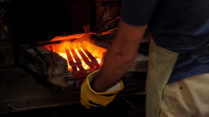 一个铁匠把两把炽热的金属剑放在燃烧的煤上。