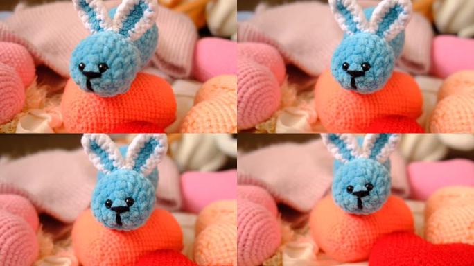 一个钩针玩具可爱的兔子和许多针织彩色心形。兔子毛绒玩具蓝绿色。Amigurumi爱好