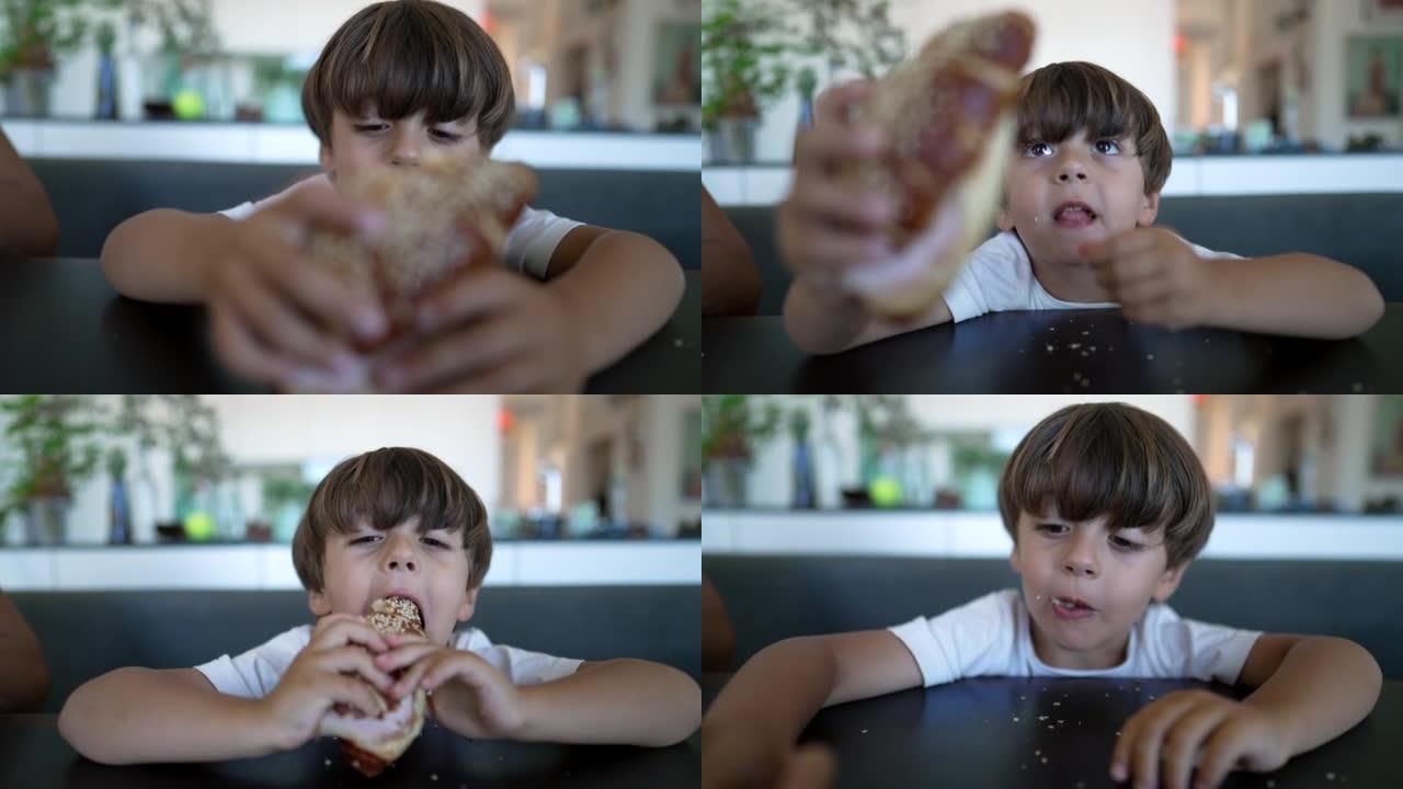 一个小男孩抓着面包，坐在桌子上吃了一口碳水化合物食物