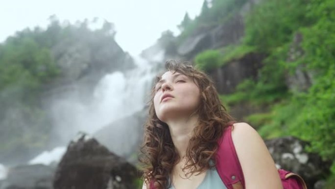 坐在挪威山区强大瀑布附近的女人的特写肖像