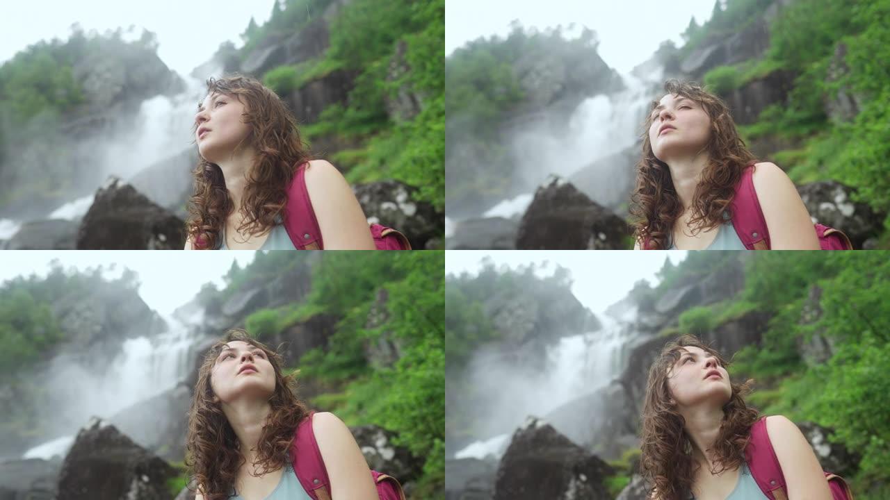 坐在挪威山区强大瀑布附近的女人的特写肖像