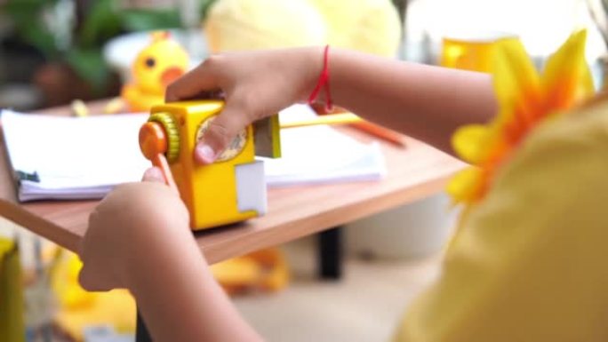亚洲小学女孩服装黄色t恤在露台做作业，远程学习，削尖铅笔