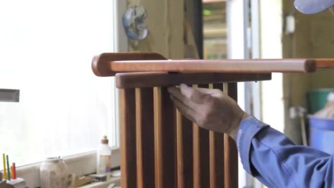 他车间里的一个木匠组装了一把手工制作的椅子，用螺丝拧紧螺栓，用六角扳手固定。检查椅子的强度。家居装饰