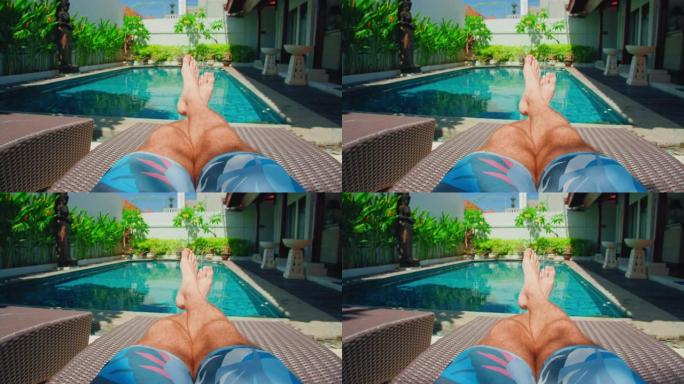 晒太阳床上男性腿的轮廓。蓝色游泳池水，度假放松。长着浓密深色体毛的家伙脚。休闲区，贵妃椅。