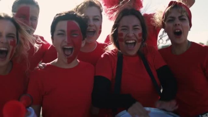 多代红色运动迷在支持他们的球队时尖叫-足球女支持者在比赛中玩耍-冠军和获胜概念