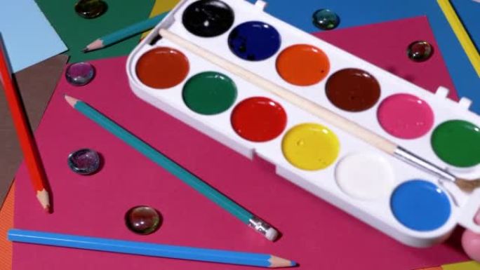 女性的手在桌子上放一个水彩画调色板。缩放