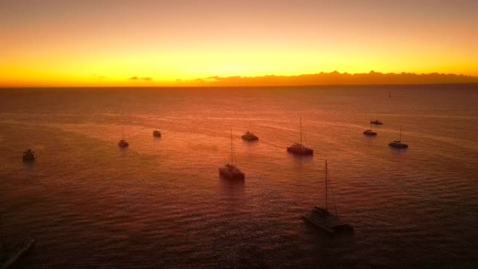 日落时停泊在锚帆船旅游游艇和高桅杆双体船上的轮廓的鸟瞰图。平静的海面上美丽的自然景观