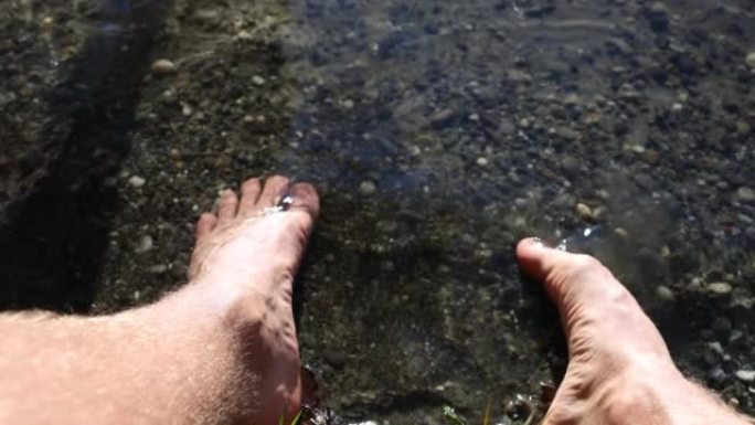 特写镜头，一个人的脚在河里在岸边放松