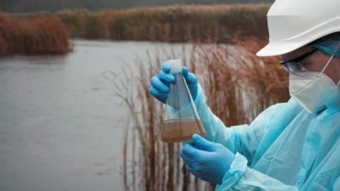 年轻的科学家生物学家分析水和土壤的污染，用烧瓶寻找专业知识的人。环境污染水样存在的问题