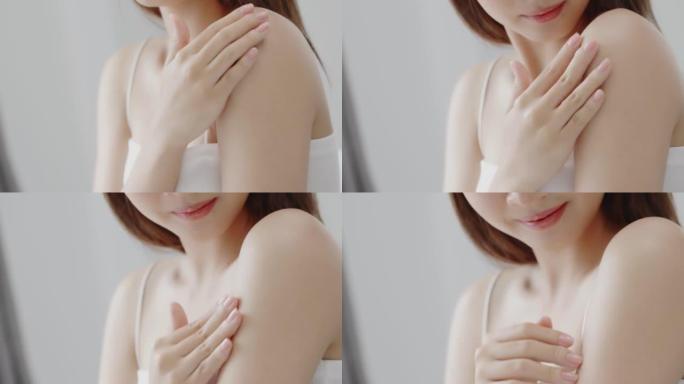 特写亚洲女性在肩膀上涂抹保湿面霜乳液。健康护肤理念。