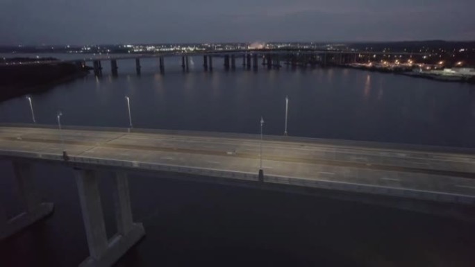 无人驾驶飞机拍摄黄昏时在阴暗的天空下在宁静的湖上的一座长桥