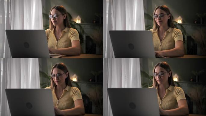 女人用笔记本电脑远程工作，坐在家里的桌子上。年轻的金发女孩在键盘电脑上打字，在室内学习在线课程。严肃