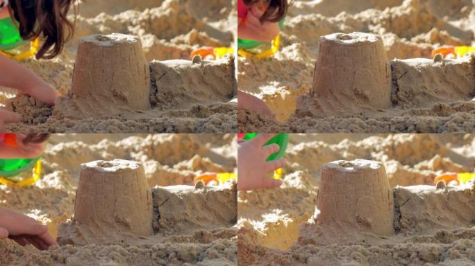 特写，一个沙饼，孩子的手在上面放一个沙子的表格。操场上或沙滩上的夏季儿童游戏