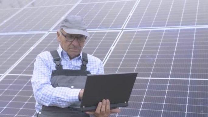 工程师在太阳能电池板前的笔记本电脑上工作。