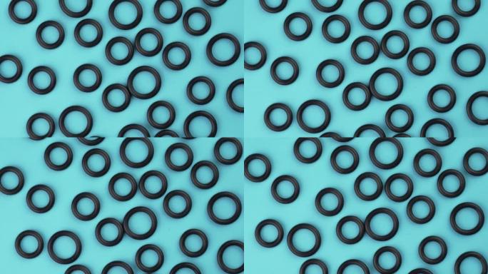 蓝色背景上圆形几何形状的黑色弹性橡胶密封垫片的俯视图