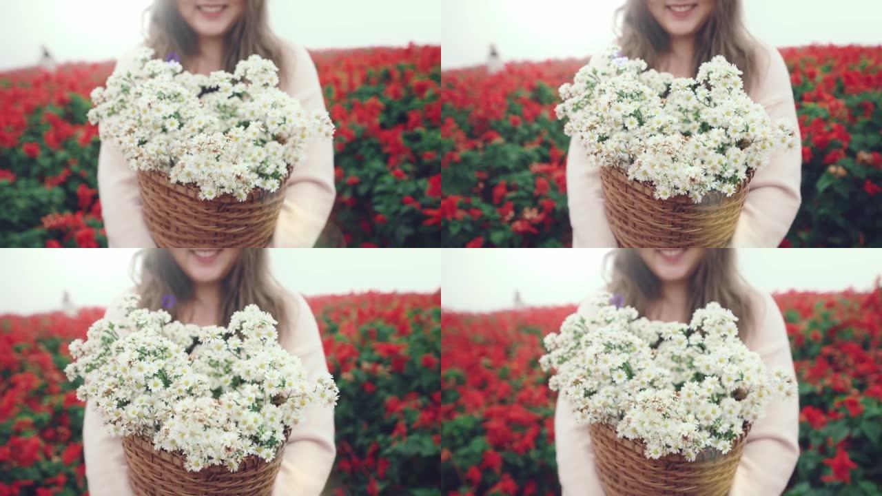 女人的笑脸走路，拿着白色雏菊的篮子。背景是一片红花