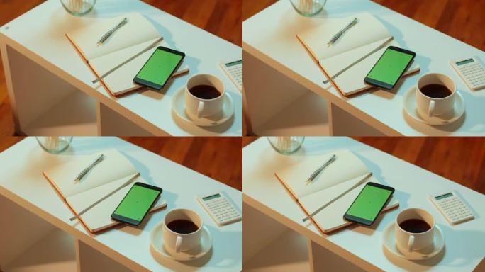 在舒适的咖啡馆环境中，咖啡桌上的绿屏手机