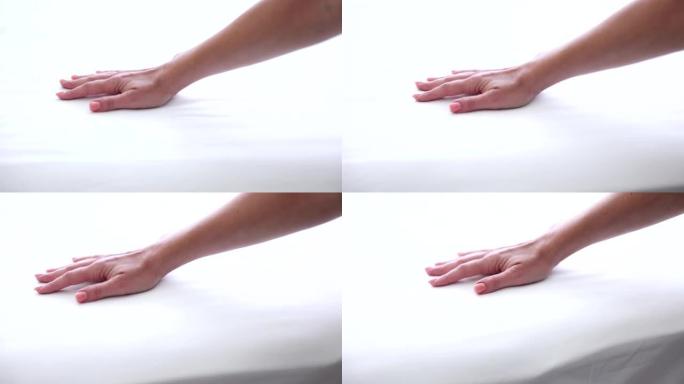 女性手部测试白色矫形床垫的硬度