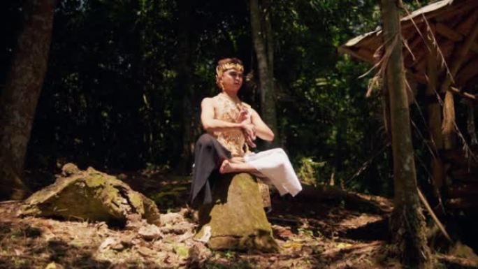 一个戴着金冠的亚洲人坐在石头上，光着膀子在森林里冥想