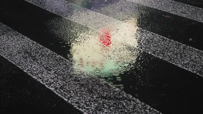 特写雨滴落在水坑上，灯光反射在城市人行道上。雨滴在城市街道的湿沥青上，雨滴落在斑马十字路口，抽象4k