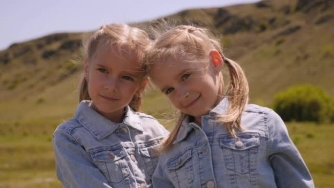 两个双胞胎小女孩的肖像在美丽的山峦中。