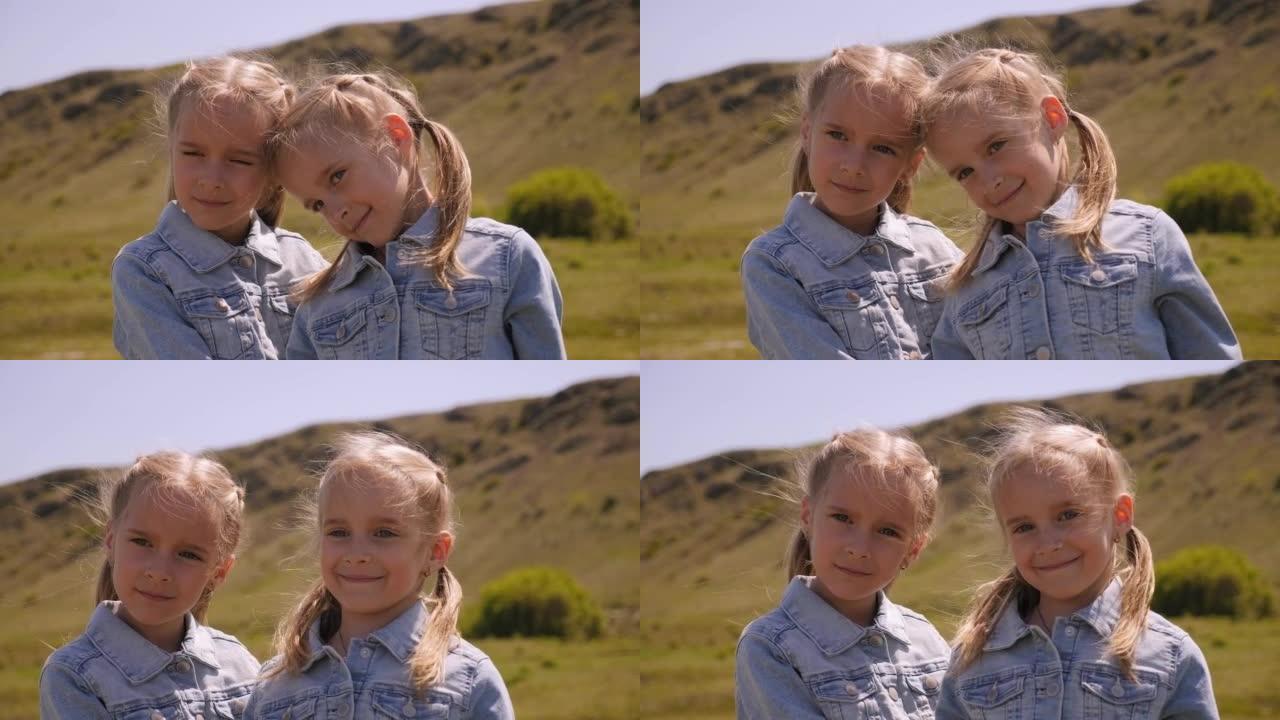 两个双胞胎小女孩的肖像在美丽的山峦中。