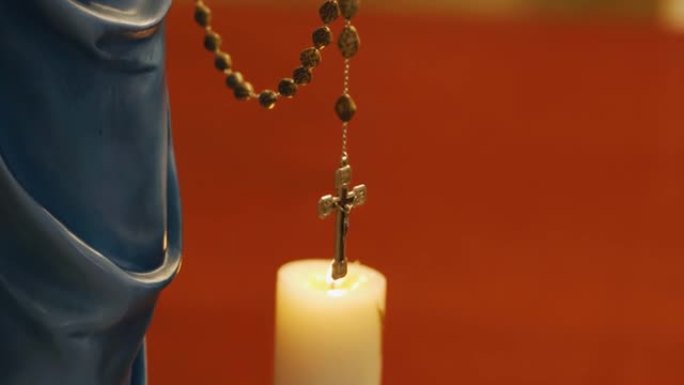 寺庙里燃烧的蜡烛旁边，在铁链上挂着耶稣受难像。物体的特写拍摄