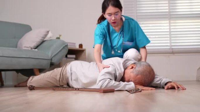 亚洲护理员帮助老年男性免于摔倒在地。老年男性患者接受物理治疗时心脏病发作。护士协助救援概念。