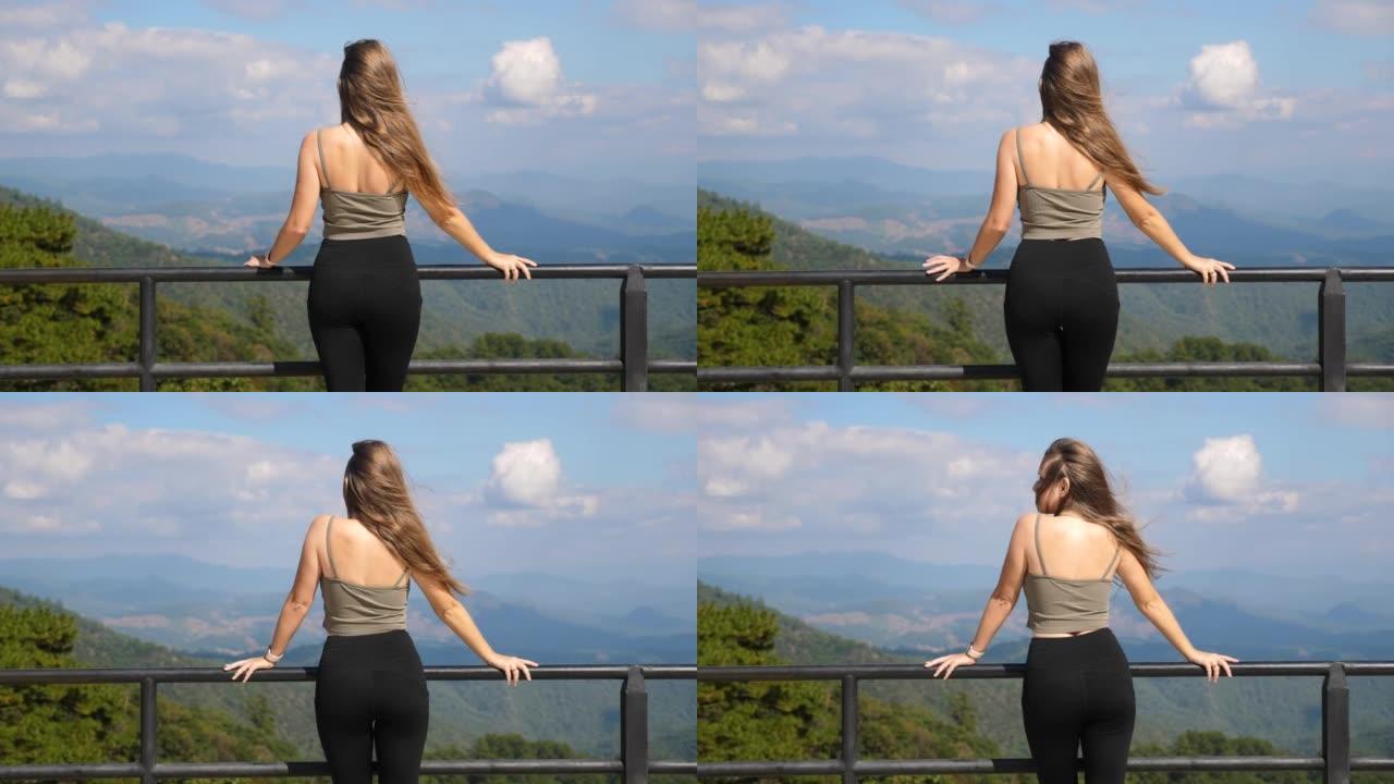千禧一代年轻女子在山顶上，欣赏山谷美景