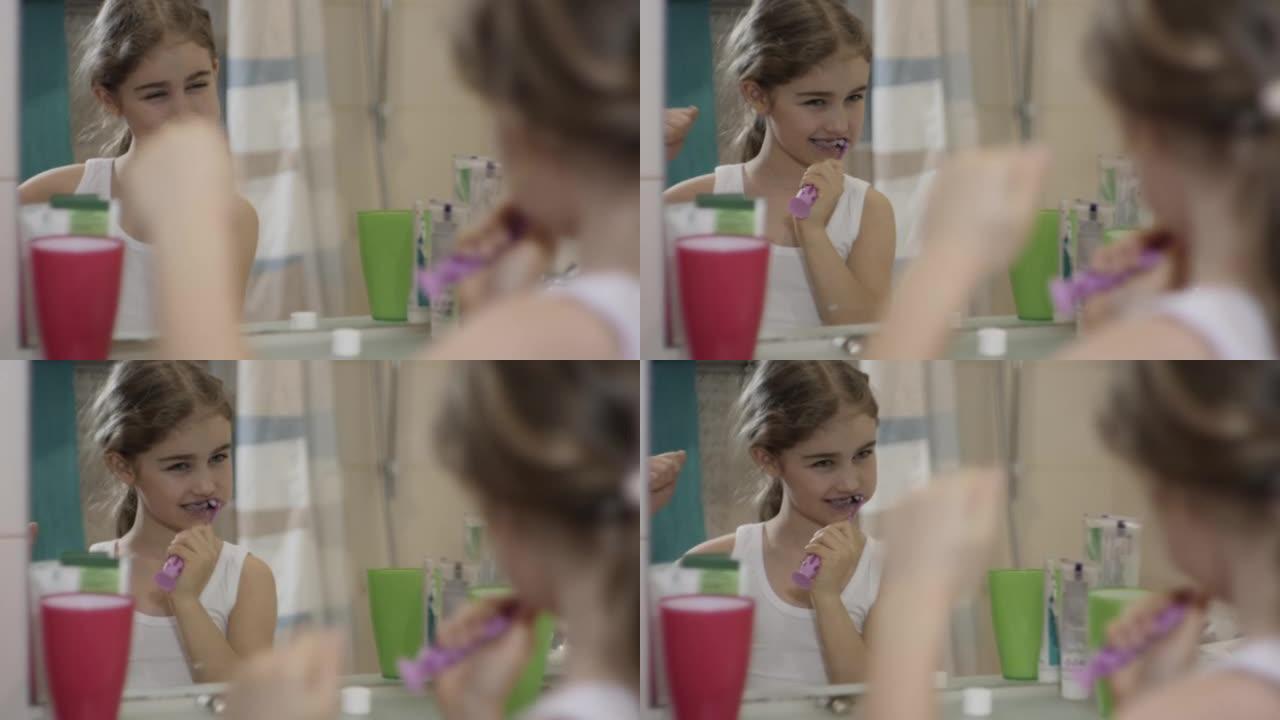 肖像年轻的小女孩在浴室刷牙，看着镜子反射。日常口腔卫生。快乐肖像可爱的高加索无牙儿童在浴室刷牙。