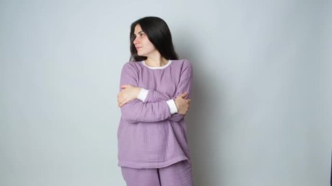 一个穿着紫色保暖睡衣的黑发女人拥抱自己，享受着舒适的睡衣
