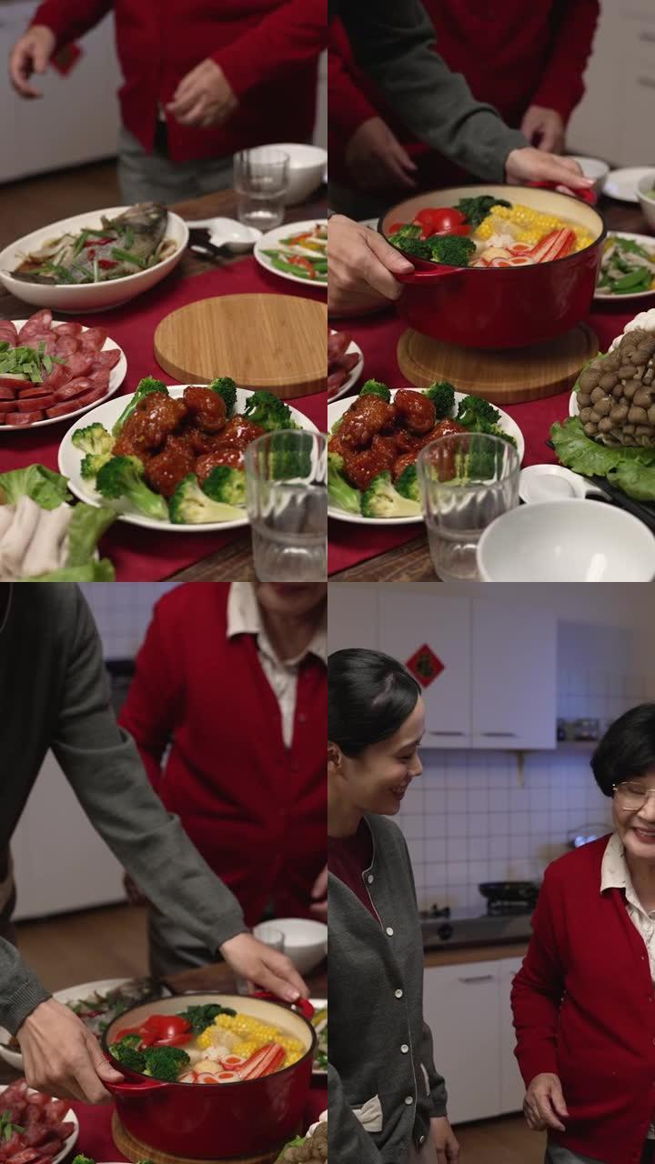 竖屏:亚洲媳妇和大妈在家里准备年夜饭时，在桌子上端着一锅热汤。文论阁翻译:财运