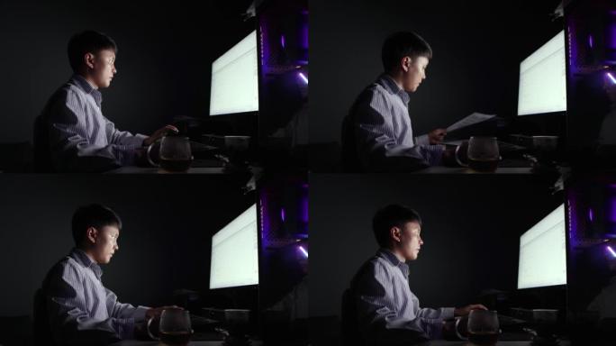 晚上，一个亚洲人在电脑前工作-年轻人的生活方式