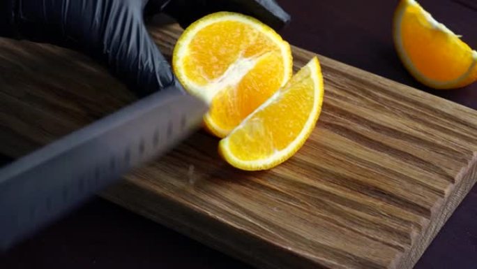 男子用菜刀在木砧板上切成生橙。家庭烹饪概念。特写