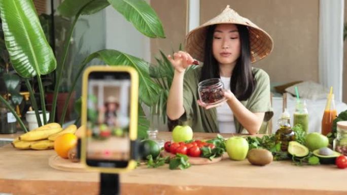 美丽微笑的亚洲年轻女性博主传统锥形帽子烹饪有机健康食品